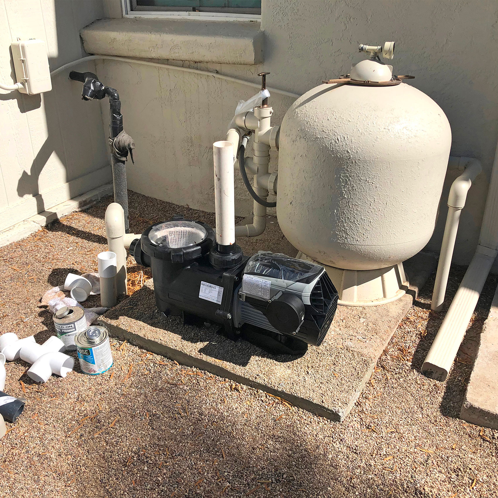 Pompe de piscine et réservoir de filtration installés à l'extérieur près d'un bâtiment.