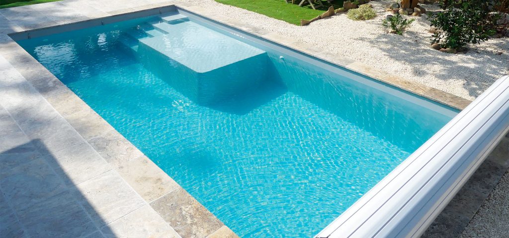 Piscine rectangulaire moderne avec couverture automatique intégrée dans un jardin soigné.